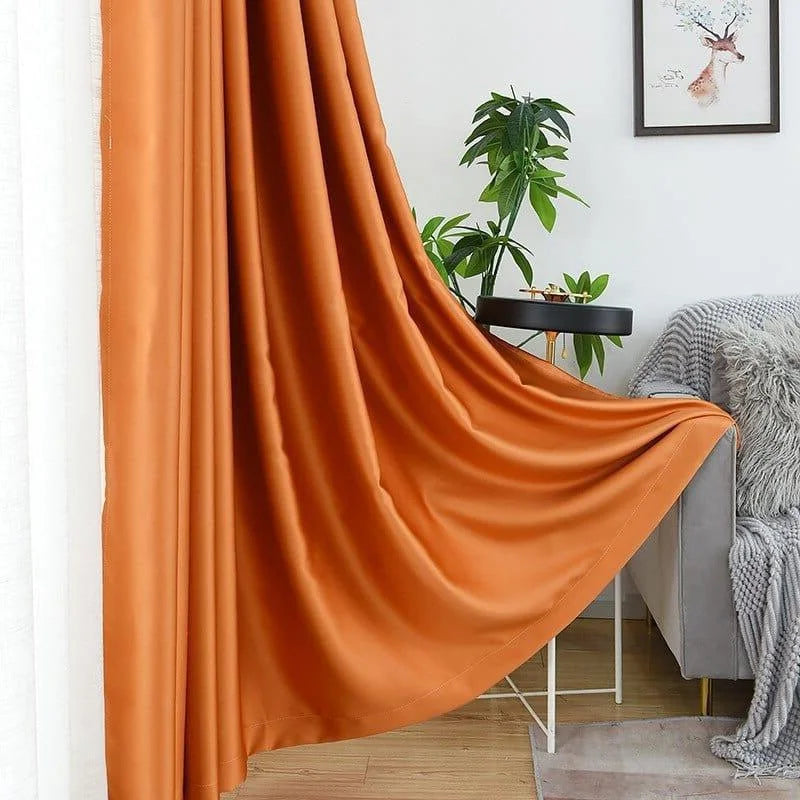 Rideau élégant de couleur orange ajoutant une touche moderne et chaleureuse à votre salon. Idéal pour créer une ambiance raffinée, il s'accorde parfaitement avec une décoration intérieure contemporaine. Le rideau est présenté dans un salon lumineux avec des éléments de décoration harmonieux, notamment une plante verte et un cadre mural artistique. Parfait pour habiller vos fenêtres tout en offrant une performance décorative optimale.