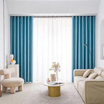 Salon moderne avec canapé beige, rideaux bleu turquoise et voilage blanc, fauteuil design et table basse circulaire dorée. Ambiance lumineuse et épurée, idéale pour un style contemporain et élégant.