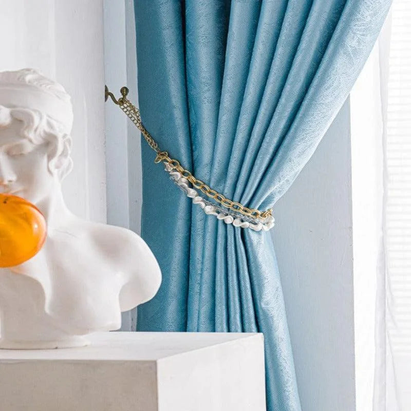 Rideau élégant de couleur bleue avec embrasse dorée et détails décoratifs, idéal pour ajouter une touche de sophistication à votre intérieur. Ce rideau apporte une ambiance raffinée à tout salon ou chambre, parfait pour la décoration maison. Découvrez comment ce design chic peut transformer votre espace.