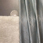 Rideau élégant gris argenté aux motifs géométriques, créant une ambiance moderne et sophistiquée dans le salon. Complété par un tapis moelleux blanc, ajoutant une touche de confort et de luxe à votre décoration intérieure. Parfait pour intégrer une note de design contemporain claire et chic à n'importe quelle pièce.