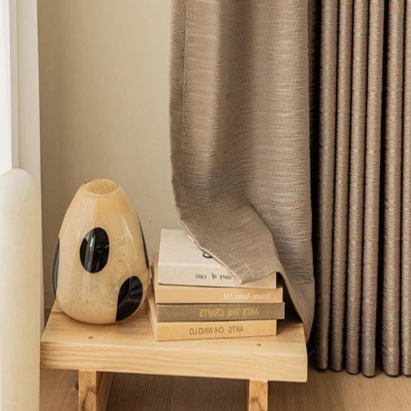 Rideau élégant beige, parfait pour une décoration intérieure moderne. Idéal pour un salon ou une chambre, ce rideau apporte une touche de sobriété et de style. Avec une finition soignée, il s'accorde parfaitement avec des meubles en bois clair. Accessoirisé d'un vase décoratif et de quelques livres, il crée une ambiance chaleureuse et accueillante.