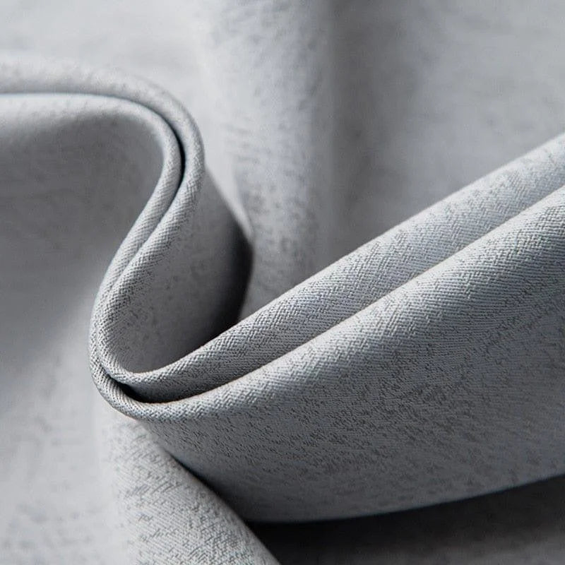 Gros plan sur un tissu gris avec un motif subtil, idéal pour la décoration intérieure. Ce textile raffiné offre une élégance moderne, parfait pour les rideaux ou le recouvrement de meubles. Découvrez la qualité et le style intemporel de ce tissu polyvalent pour votre maison.