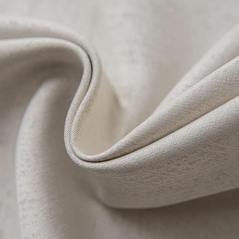 Gros plan d'un tissu élégant beige, idéal pour confection et ameublement, mettant en valeur des plis subtils et une texture délicate. Accessoire indispensable pour décoration intérieure.