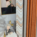 Décoration intérieure élégante avec rideaux modernes aux motifs géométriques orange et gris, tableau artistique contemporain et figurine de décoration originale, créant une ambiance chaleureuse et artistique dans le salon. Idéal pour sublimer votre espace de vie avec une touche de design unique.