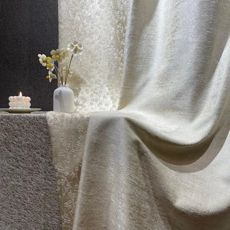 Textile d'ameublement élégant en teinte crème exposé avec raffinement, accompagné d'une bougie décorative et d'un vase avec des fleurs blanches et jaunes, parfait pour ajouter une touche de sophistication à votre décor intérieur. Idéal pour créer une ambiance chaleureuse et accueillante.