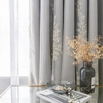 Rideaux élégants avec motifs floraux brodés, ajoutant une touche sophistiquée à votre intérieur. Décoration chic sur une table en verre, ornée d'un vase design et de perles décoratives. Parfait pour créer une ambiance raffinée et accueillante dans votre salon ou chambre.