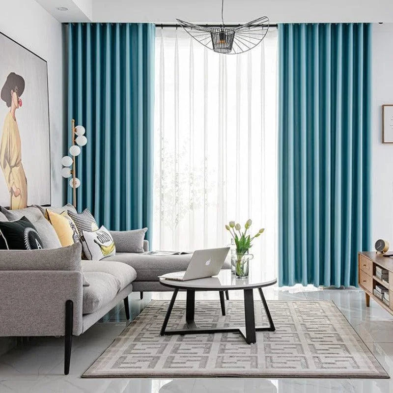Salon moderne et élégant avec rideaux turquoise, canapé d'angle gris, coussins décoratifs colorés et table basse tendance. Ambiance chaleureuse et lumineuse pour un espace convivial et accueillant. Idéal pour un intérieur contemporain sophistiqué.