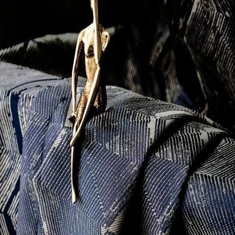Statue artistique moderne sur tissu texturé bleu foncé, motif géométrique élégant, décoration intérieure contemporaine, mise en scène design pour un intérieur sophistiqué.