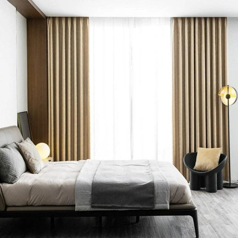 Chambre moderne avec lit double élégant, rideaux beige ajoutant une touche chaleureuse, et chaise design avec coussin. Luminaire contemporain et parquet sombre. Idéal pour une décoration intérieure chic et épurée. Solution parfaite pour un espace de repos confortable et stylé.
