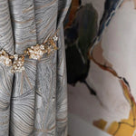 Rideau élégant avec motif artistique en tons de gris, agrémenté d'une embrasse florale délicate, idéal pour apporter une touche sophistiquée et stylée à votre intérieur tout en ajoutant une élément de décoration chic et raffiné. Parfait pour créer une ambiance chaleureuse et moderne dans votre salon ou chambre.