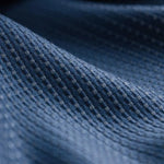 Texture détaillée d'un tissu bleu avec motif en relief, offrant un aperçu de la finition de haute qualité et du design élégant idéal pour les vêtements ou la décoration intérieure.