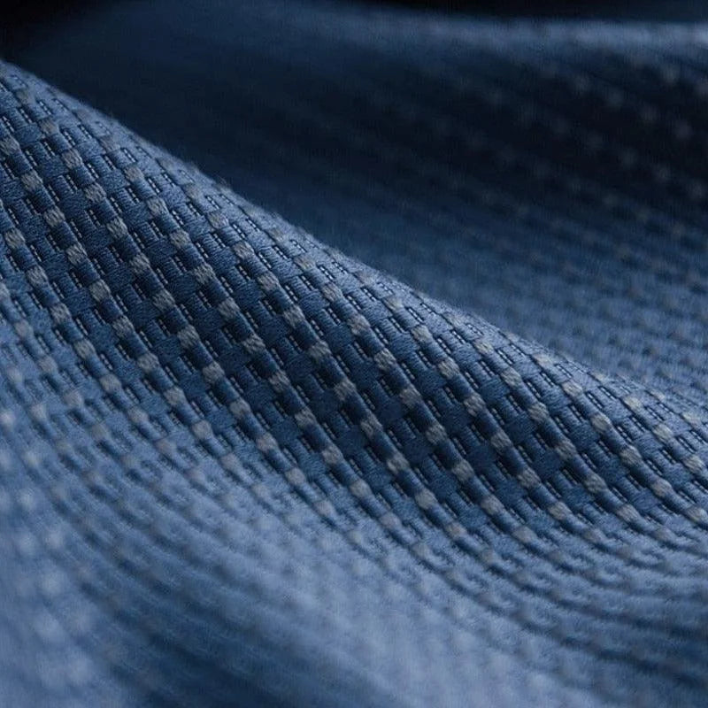 Texture détaillée d'un tissu bleu avec motif en relief, offrant un aperçu de la finition de haute qualité et du design élégant idéal pour les vêtements ou la décoration intérieure.