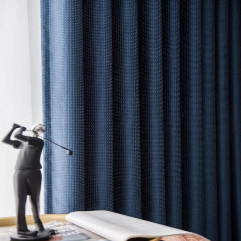 Rideaux bleus élégants pour salon avec motif subtil, statue décorative de golfeur sur une table en bois, ambiance raffinée et moderne dans un intérieur soigné.