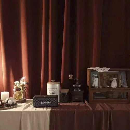 Aménagement d'intérieur chaleureux avec éléments vintage et modernes, comprenant une enceinte élégante, un moulin à café rétro et des accessoires décoratifs sur une table décorée. Ambiance feutrée avec rideaux sombres, idéal pour un style de vie cocooning et raffiné.