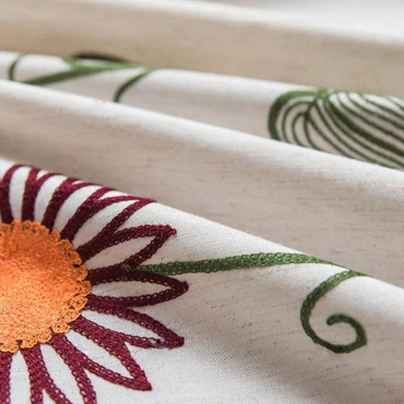Tissu décoratif avec motif floral brodé, présentant une fleur orange et bordeaux sur fond clair, idéal pour ajouter une touche naturelle et élégante à votre intérieur. Parfait pour la décoration de la maison, ce tissu embellit vos espaces tout en apportant une ambiance chaleureuse et accueillante.