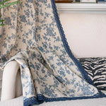Couverture décorative avec imprimé floral bleu et bordure dentelée, parfaite pour ajouter une touche élégante à votre salon. Idéale pour habiller un canapé ou un fauteuil, cette pièce crée une ambiance chaleureuse et accueillante dans votre intérieur.