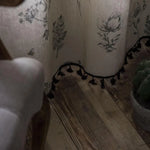 Rideau décoratif à motifs floraux avec bordure à pompons noirs, idéal pour ajouter une touche élégante et naturelle à votre intérieur. Sa conception raffinée s'intègre parfaitement dans un salon ou une chambre.
