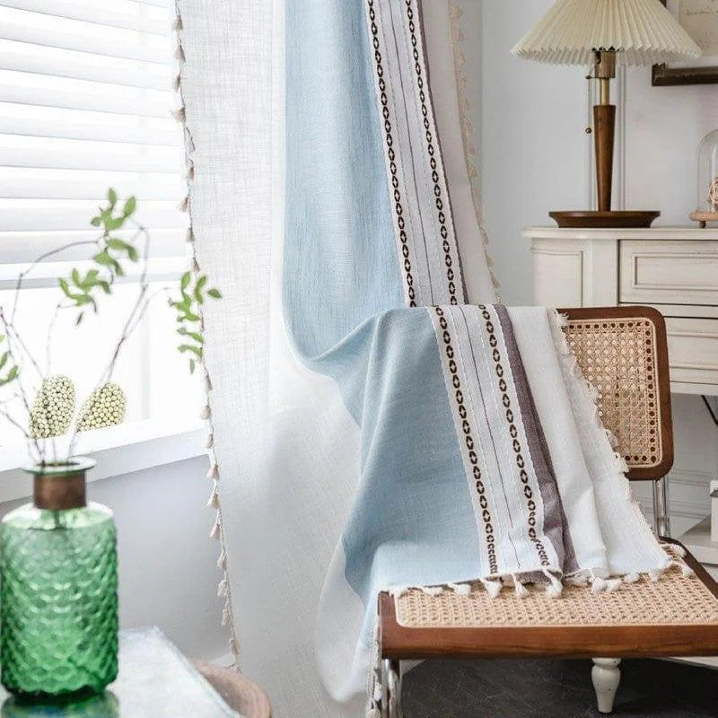 Rideaux décoratifs bleu et blanc avec motifs élégants, ornant une pièce lumineuse. Idéal pour ajouter une touche de style et chaleur à votre intérieur. Accessoire parfait pour rehausser la décoration de votre salon ou chambre. Effet zen assuré avec un filtre doux pour la lumière.