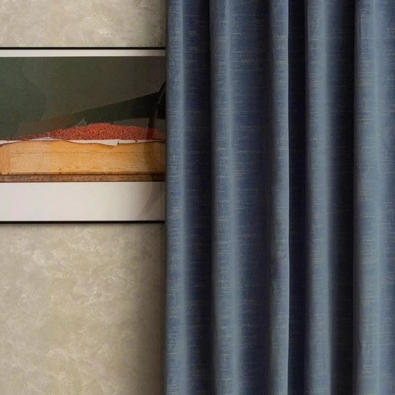 Rideau bleu élégant en arrière-plan, intégré dans un intérieur moderne avec un tableau encadré. Idéal pour ajouter une touche contemporaine et sophistiquée à votre salon ou chambre. Parfait pour créer une ambiance cosy tout en assurant une décoration épurée.