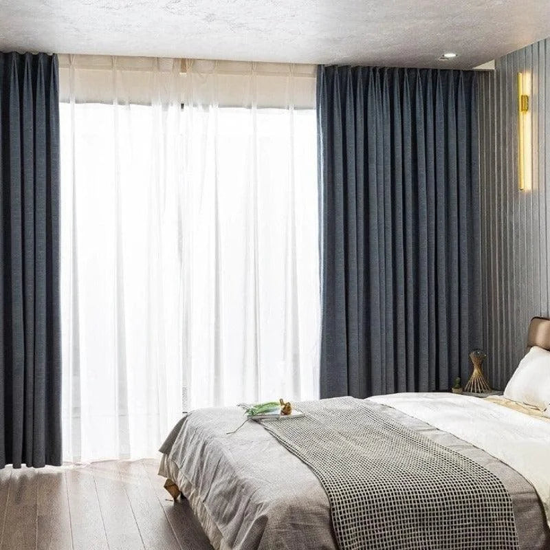 Chambre moderne avec rideaux opaques gris foncé et voilages blancs, éclairage mural design, lit double confortable, ambiance élégante et apaisante, idéal pour une décoration intérieure contemporaine.