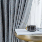 Rideaux élégants avec motifs paisley, accompagnés d'une tasse noire sur une table dorée. Parfaits pour ajouter une touche de sophistication à votre décoration intérieure, ces rideaux aux tons bleus et blancs créent une atmosphère chic et apaisante dans votre salon. Accessoire de luxe pour une ambiance chaleureuse et accueillante.