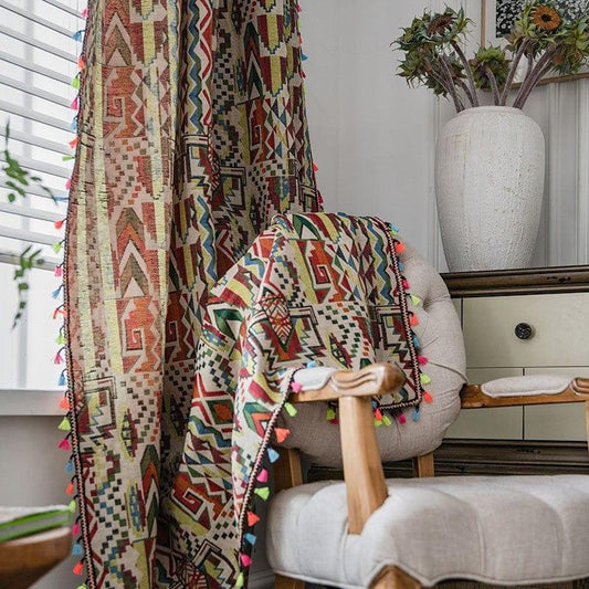 Tenture bohème colorée avec motifs géométriques et franges colorées drapée sur un fauteuil dans un intérieur lumineux. Décoration murale et ambiance cosy avec vase décoratif et éléments naturels. Parfait pour ajouter une touche artistique à votre salon.
