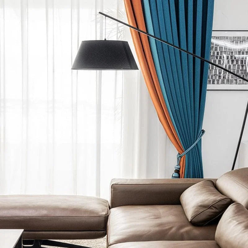 Intérieur moderne et élégant avec un canapé confortable, une lampe sur pied design et des rideaux bicolores bleu et orange. Ambiance chaleureuse et sophistiquée, idéale pour un salon contemporain. Acheter des meubles de qualité pour transformer votre espace de vie.