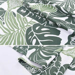 Image montrant un tissu avec un motif de feuilles tropicales vertes sur fond blanc. Idéal pour ajouter une touche exotique à votre décoration intérieure ou pour la confection de vêtements estivaux. Design élégant et contemporain inspiré par la nature, parfait pour apporter une atmosphère fraîche et naturelle à votre espace.