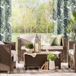Salon de jardin élégant avec fauteuils confortables et canapé beige, idéal pour des moments de détente en plein air. Les coussins verts apportent une touche de fraîcheur, tandis que les rideaux à motifs végétaux et les lampes décoratives créent une ambiance naturelle et apaisante. Parfait pour profiter des beaux jours dans un cadre convivial et relaxant.