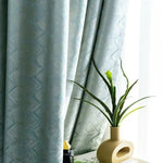 Rideaux élégants de couleur bleue avec motif chevrons, ajoutant une touche sophistiquée à votre intérieur. Parfait pour un salon moderne. Accessoirisé par une plante verte dans un vase design, idéal pour créer une ambiance naturelle et apaisante.