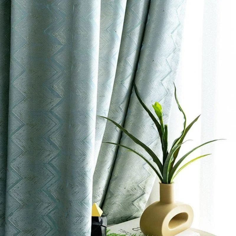 Rideaux élégants de couleur bleue avec motif chevrons, ajoutant une touche sophistiquée à votre intérieur. Parfait pour un salon moderne. Accessoirisé par une plante verte dans un vase design, idéal pour créer une ambiance naturelle et apaisante.