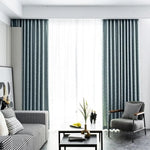 Rideaux modernes bleu foncé dans un salon élégant, illuminant la pièce avec une lumière diffuse. Canapé et fauteuil contemporains avec motifs géométriques, table basse design avec décoration minimaliste. Parfait pour une décoration d'intérieur raffinée et moderne. Idéal pour créer une ambiance chaleureuse et accueillante dans un espace de vie.