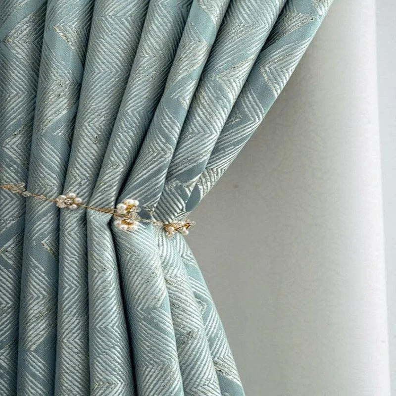Rideau élégant bleu avec motif géométrique, attaché avec une embrasse décorative ornée de détails perlés. Idéal pour ajouter une touche raffinée à votre intérieur et filtrer délicatement la lumière dans votre salon ou chambre. Parfait pour les décors modernes à la recherche de style et de fonctionnalité.