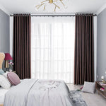 Chambre élégante avec rideaux longs et sombres encadrant une grande fenêtre, apportant une touche sophistiquée à la décoration intérieure. Le lit est joliment habillé avec des coussins et un couvre-lit assortis, offrant un espace accueillant et relaxant. Le mobilier moderne et les accessoires raffinés complètent le look luxueux et chaleureux. Parfait pour créer une ambiance reposante et stylistique dans toute chambre à coucher.