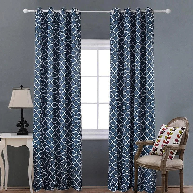 Rideaux décoratifs bleus avec motif géométrique devant une fenêtre, apportant une ambiance élégante et moderne à la pièce. Accessoirisés avec un coussin coloré sur une chaise et une lampe de table classique, ces rideaux ajoutent une touche de style sophistiqué à tout intérieur. Idéals pour bloquer la lumière et améliorer l'intimité, ces rideaux sont parfaits pour le salon ou la chambre.