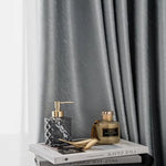 Rideaux élégants de couleur grise, parfaits pour créer une ambiance sophistiquée dans votre salon. Accessoires de décoration modernes avec flacons de parfum et livres empilés, ajoutant une touche de raffinement à votre espace intérieur. Découvrez comment ces éléments peuvent transformer votre maison en un havre de paix chic et accueillant.