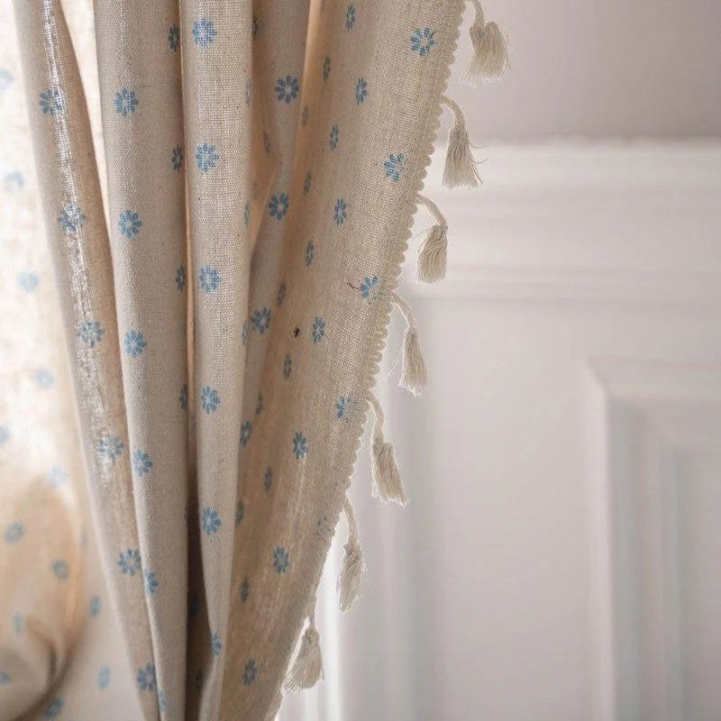 Rideau élégant beige à motifs floraux bleus, agrémenté de franges décoratives, idéal pour ajouter une touche raffinée à votre intérieur. Parfait pour les salons ou chambres, apportant une atmosphère chaleureuse et accueillante.
