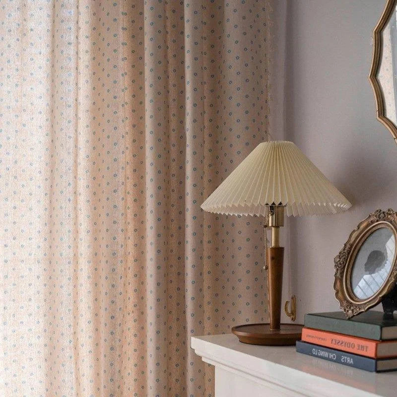 Lampe de table élégante avec abat-jour plissé sur un meuble. Tenture décorative à motifs en arrière-plan. Ambiance de chambre classique avec cadre photo ancien et livres empilés. Idéal pour un intérieur chaleureux et cosy.
