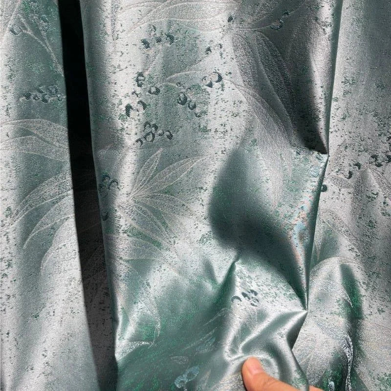 Rideau décoratif vert argenté avec motif floral élégant, présenté de près pour montrer les détails du design, idéal pour la décoration intérieure moderne et sophistiquée.