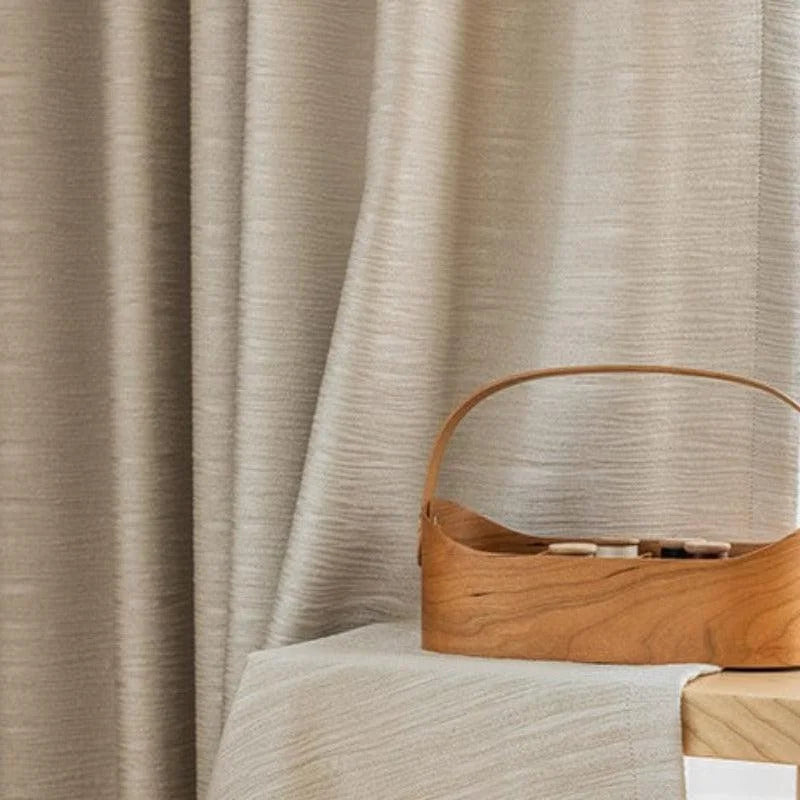 Panier décoratif élégant sur une table recouverte d'une nappe beige, avec en arrière-plan un rideau texturé assorti. Accessoire de rangement idéal pour un intérieur moderne et raffiné.