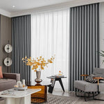 Rideaux occultants gris élégants dans un salon moderne. L'espace est décoré avec des meubles contemporains, comprenant un canapé confortable, une table basse chic, un fauteuil design et une décoration murale artistique. Luminosité douce grâce aux rideaux et à la lumière naturelle, créant une ambiance chaleureuse et accueillante. Parfait pour ajouter une touche de style et d'élégance à votre intérieur.