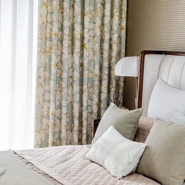 Chambre élégante avec rideaux à motifs floraux, lit confortable et coussins décoratifs, ambiance lumineuse et apaisante. Parfait pour une décoration intérieure moderne et raffinée.