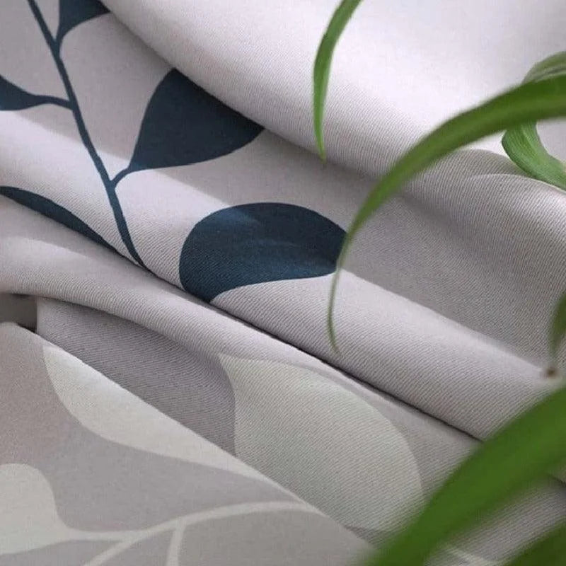 Image montrant du tissu décoratif avec motifs géométriques, idéal pour l’ameublement intérieur. Design moderne en nuances de gris et bleu, s'harmonisant parfaitement avec des plantes vertes, pour une ambiance naturelle et contemporaine.
