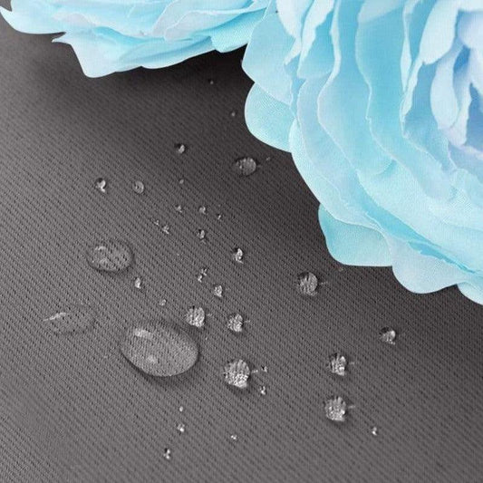 Gouttelettes d'eau sur surface imperméable avec belles fleurs bleues, illustrant l'efficacité d'une protection contre l'humidité. Idéal pour les produits d'extérieur et les accessoires résistants aux intempéries.