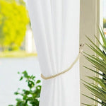 Rideau blanc élégant drapé avec embrasse torsadée, encadrant une fenêtre lumineuse avec vue sur le jardin. Accessoire de décoration intérieure moderne offrant une ambiance lumineuse et rafraîchissante.