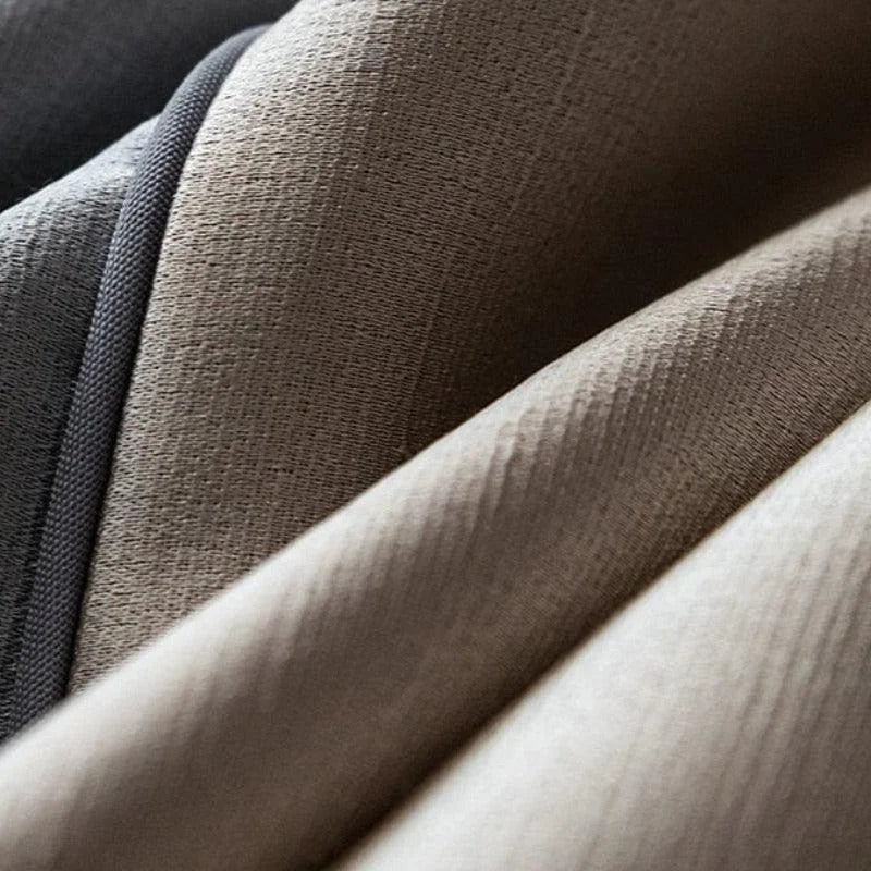 Gros plan sur un tissu épais aux nuances de gris et brun, idéal pour la décoration intérieure. L'élégance des plis et la texture ajoutent une touche sophistiquée à tout espace. Parfait pour créer une ambiance chaleureuse et moderne dans votre maison.