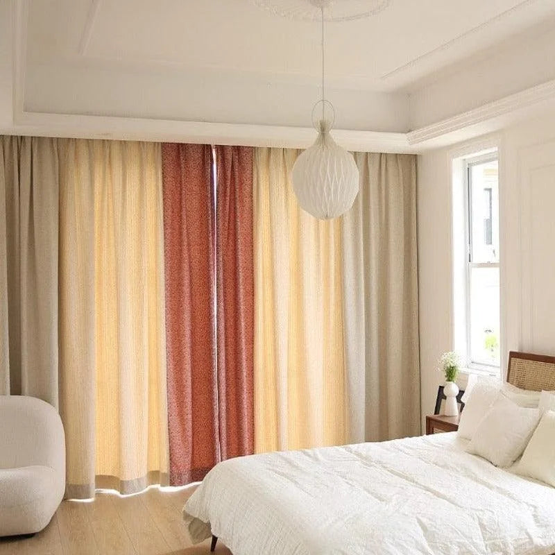 Chambre moderne élégante avec lit double et rideaux colorés créant une ambiance chaleureuse. Luminaire design suspendu pour un éclairage doux. Fenêtre apportant une lumière naturelle à la pièce. Décoration minimaliste pour un espace de repos apaisant.