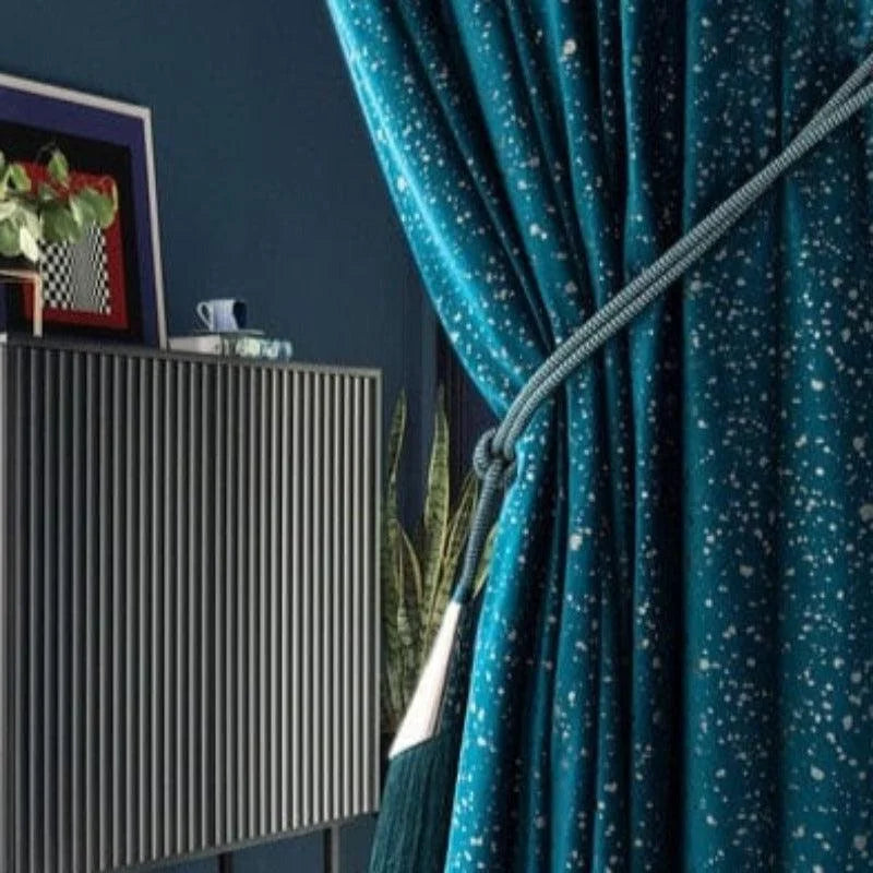 Rideau bleu à motifs élégants pour décoration intérieure, photographié dans un salon moderne avec un meuble en bois à lattes et plantes vertes en arrière-plan. Accessoire décoratif idéal pour ajouter une touche sophistiquée à votre espace de vie.
