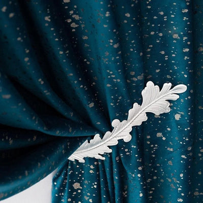 Rideau élégant bleu avec motifs argentés, orné d'un embrasse décorative en forme de feuille, idéal pour ajouter une touche de sophistication et de style à votre intérieur moderne ou classique.