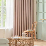 Rideau beige élégant pour salon, créant une ambiance chaleureuse et moderne. Parfait pour filtrer la lumière tout en ajoutant une touche décorative. Éléments naturels et mobilier en bois clair complètent cet espace accueillant. Solution idéale pour un intérieur contemporain et apaisant.